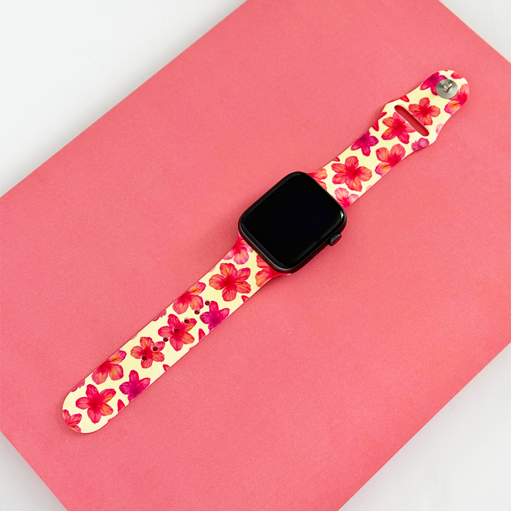 Butter yellow Apple Watch strap with hibiscus pattern on a pink surface.