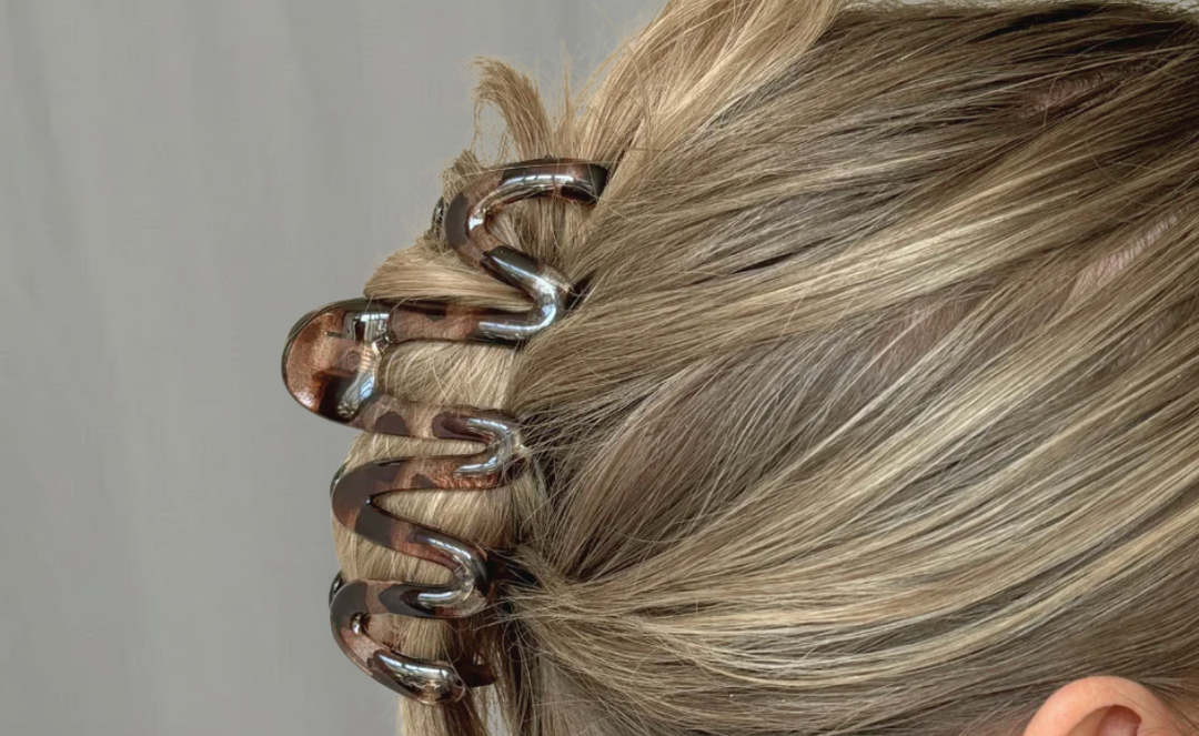 A dark brown velvet scrunchie with light pink polka dots, placed on a white surface near the corner of a wall.