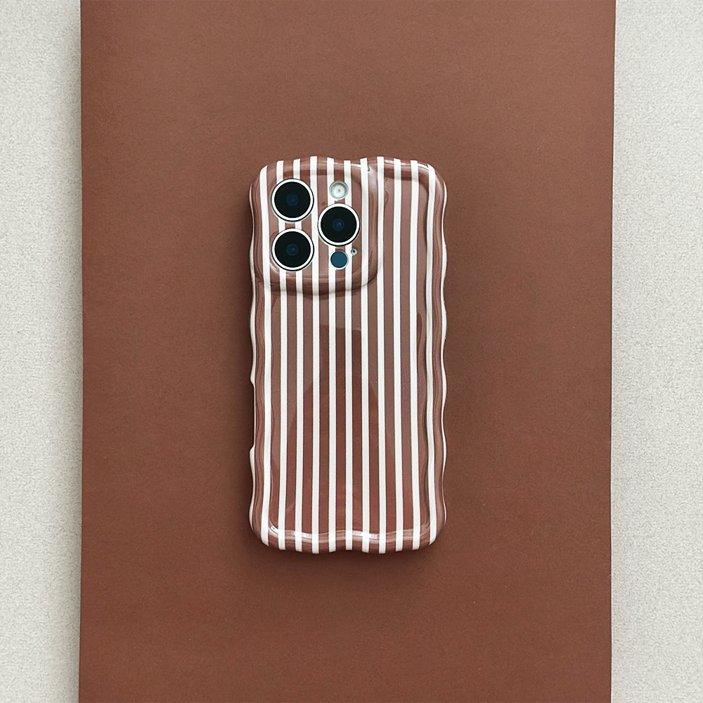 A smartphone with a case featuring vertical white and brown stripes sits on a matching brown surface. The case has a wavy edge and openings for three camera lenses and a flash.