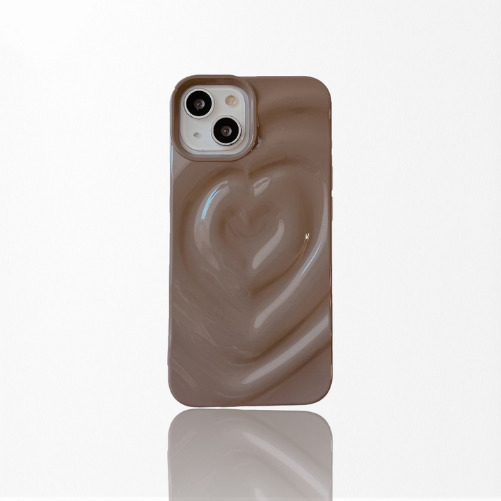 A Coconut Lane Melting Heart Phone Case in Chocolate Brown, featuring a raised, glossy 3D Melting Heart Effect design, is positioned against a plain white background. The phone's dual camera lenses are visible in the upper left corner of the case.