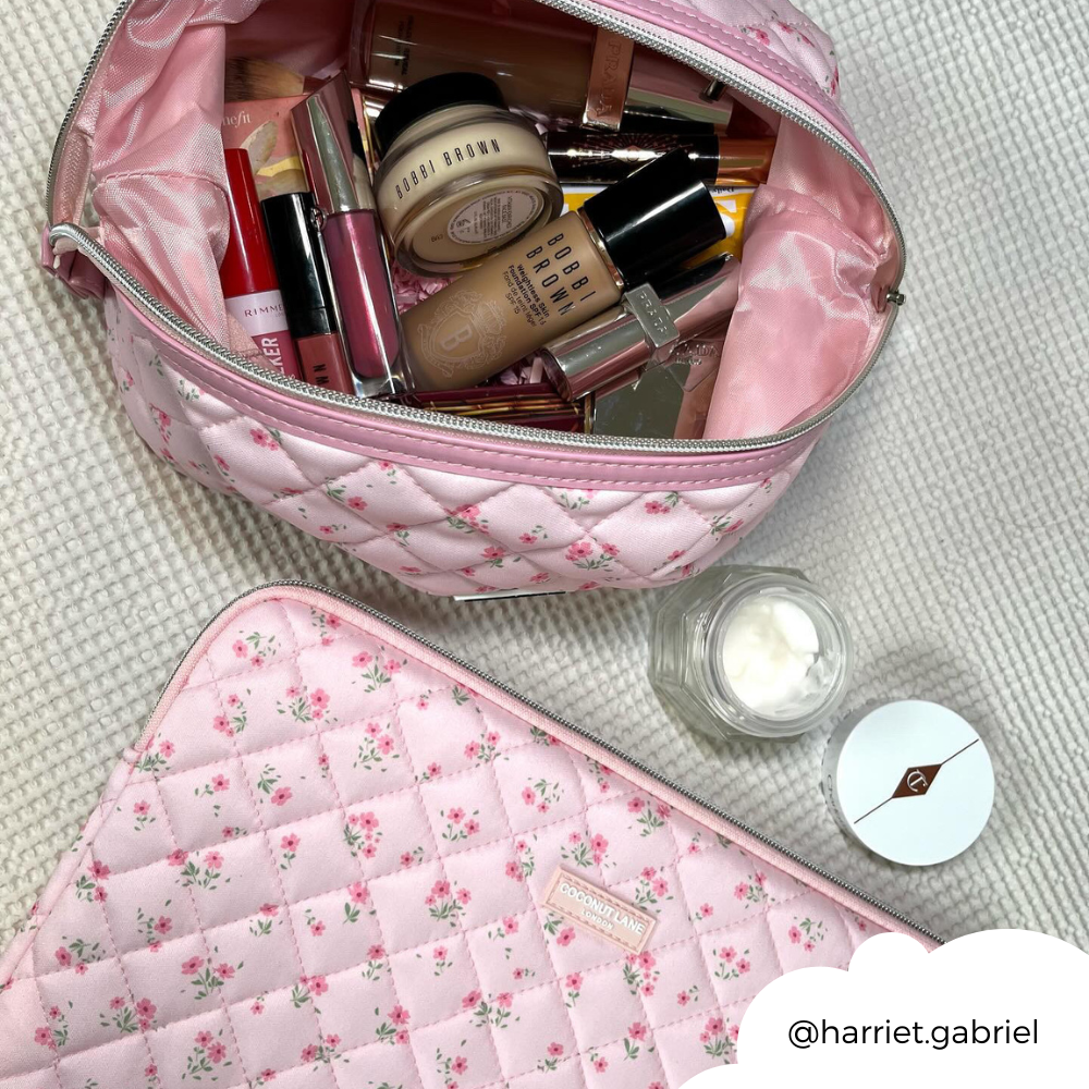 Pink quilted floral laptop sleeve with matching makeup bag and a small jar of cream arranged beside it.