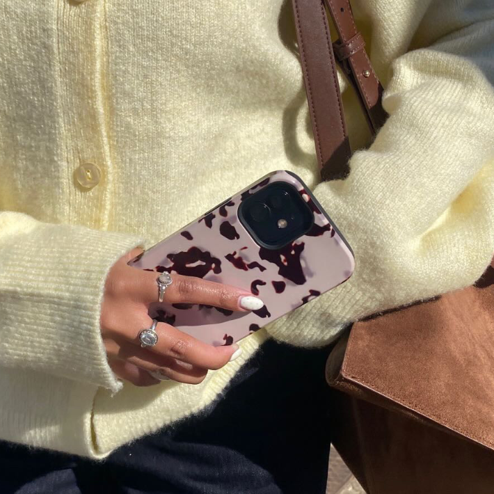 Hand with rings holding the Ivory Tort Tough phone case