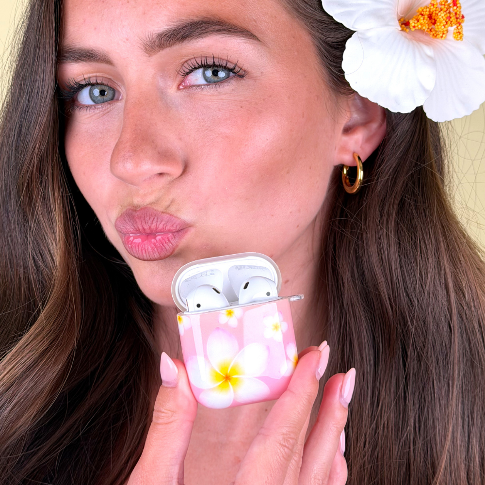 Woman holding a floral case for wireless earbuds with a flower in her hair.