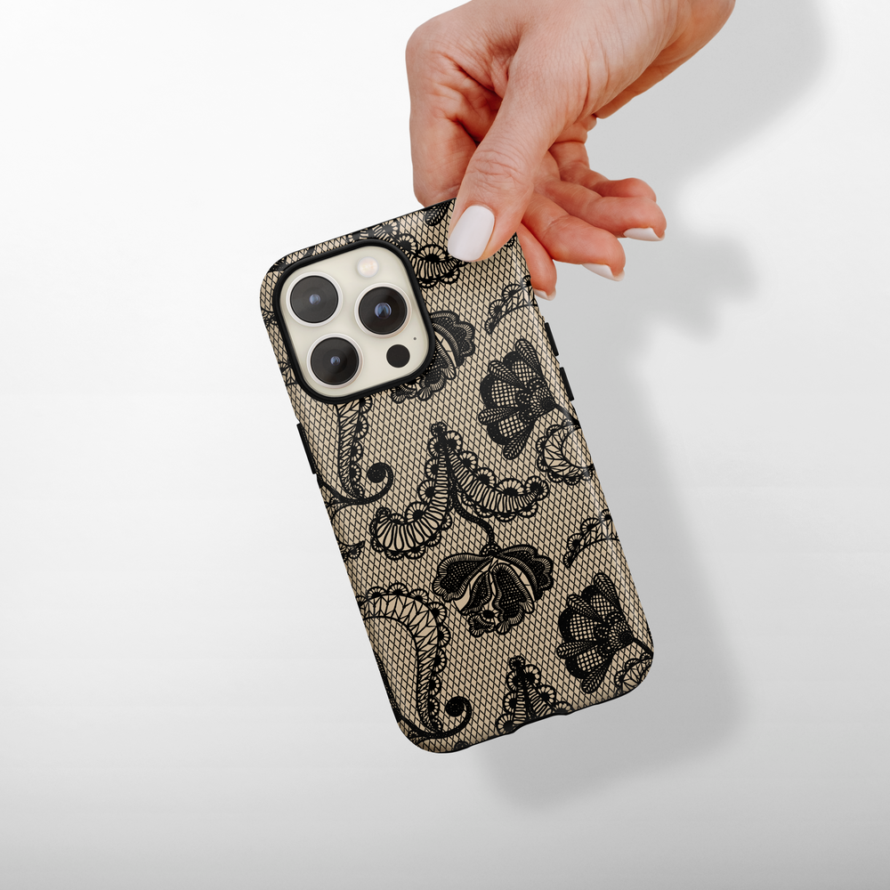 Hand holding a smartphone in a black lace and beige floral Coconut Lane Tough Phone Case.