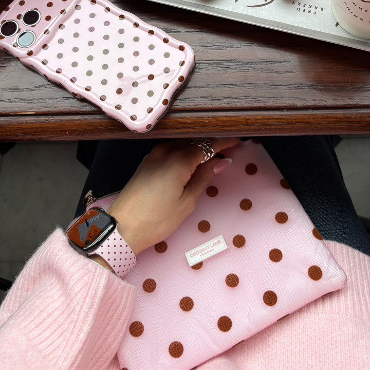 Dot Society Pink and Brown Everything Pouch. The pouch is sheer mesh material with brown polka dot detailing. Featuring in the photo is the matching Apple Watch Strap, pink with brown polka dots, alongside the matching wavy phone case.