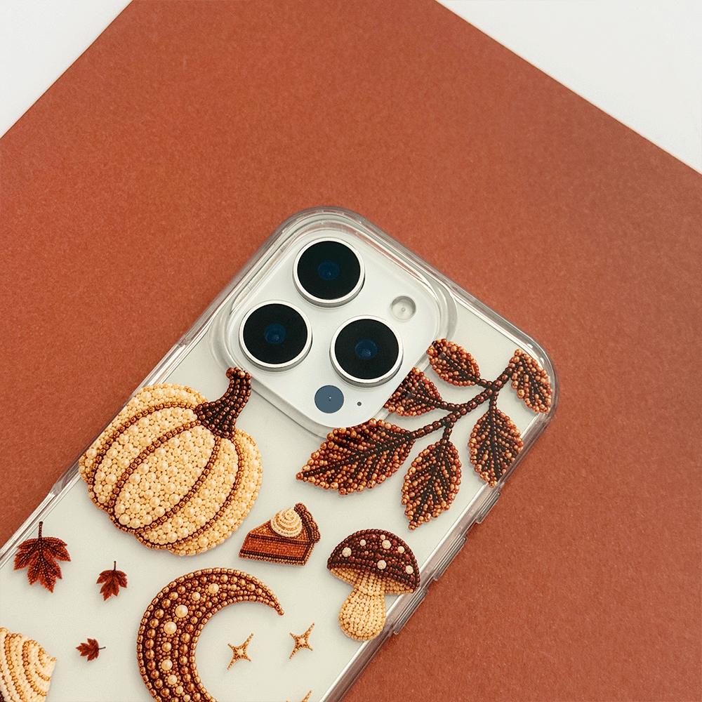 A clear phone case decorated with autumn-themed graphics including a pumpkin, moon, mushrooms, acorns, stars, and leaves.