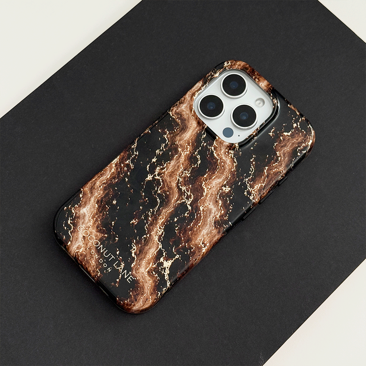 Black phone case with a swirling bronze and gold marble pattern, on a phone with three camera lenses, resting on a black surface.