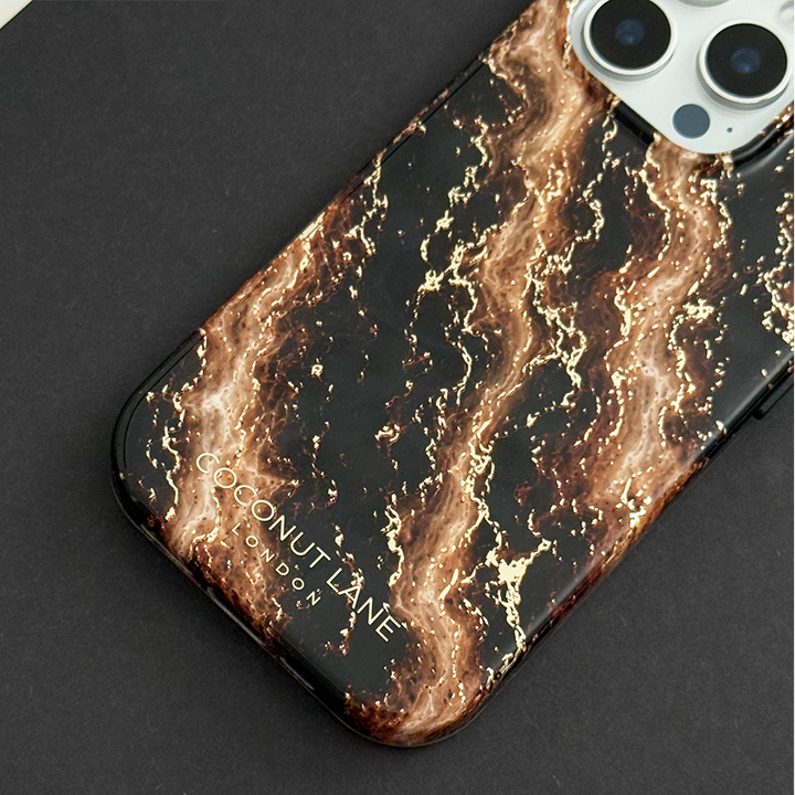 Black phone case with a swirling bronze and gold marble pattern, on a phone with three camera lenses, resting on a black surface.