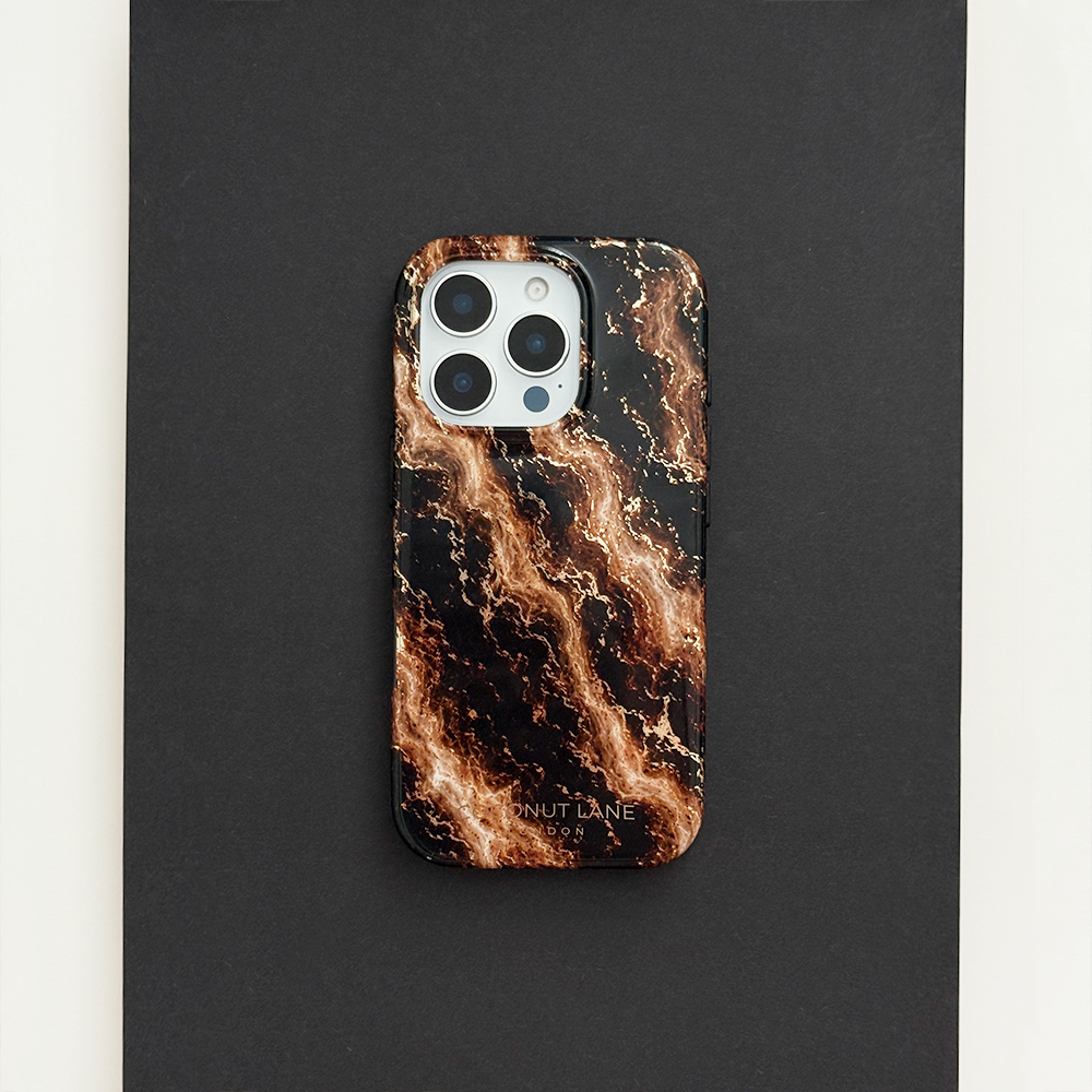 Black phone case with a swirling bronze and gold marble pattern, on a phone with three camera lenses, resting on a black surface.