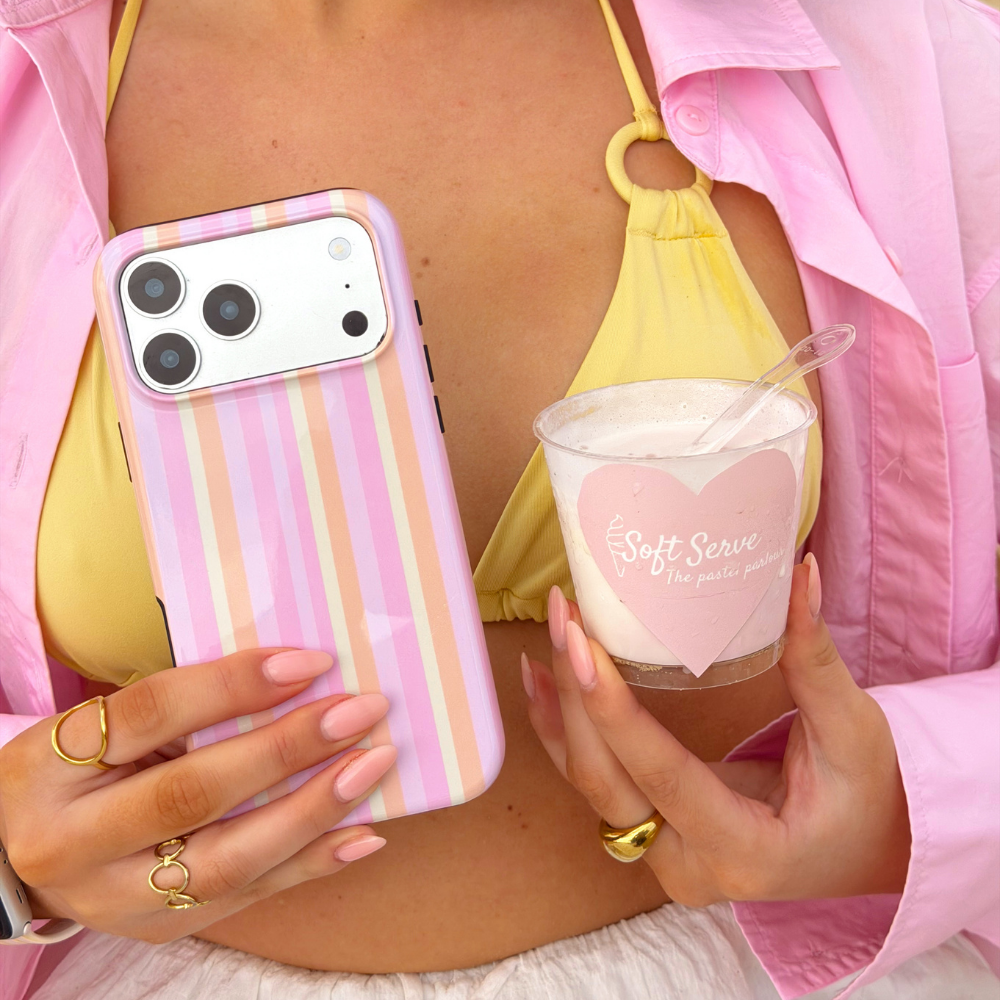Girl holding pastel stripes magsafe phone case on the beach