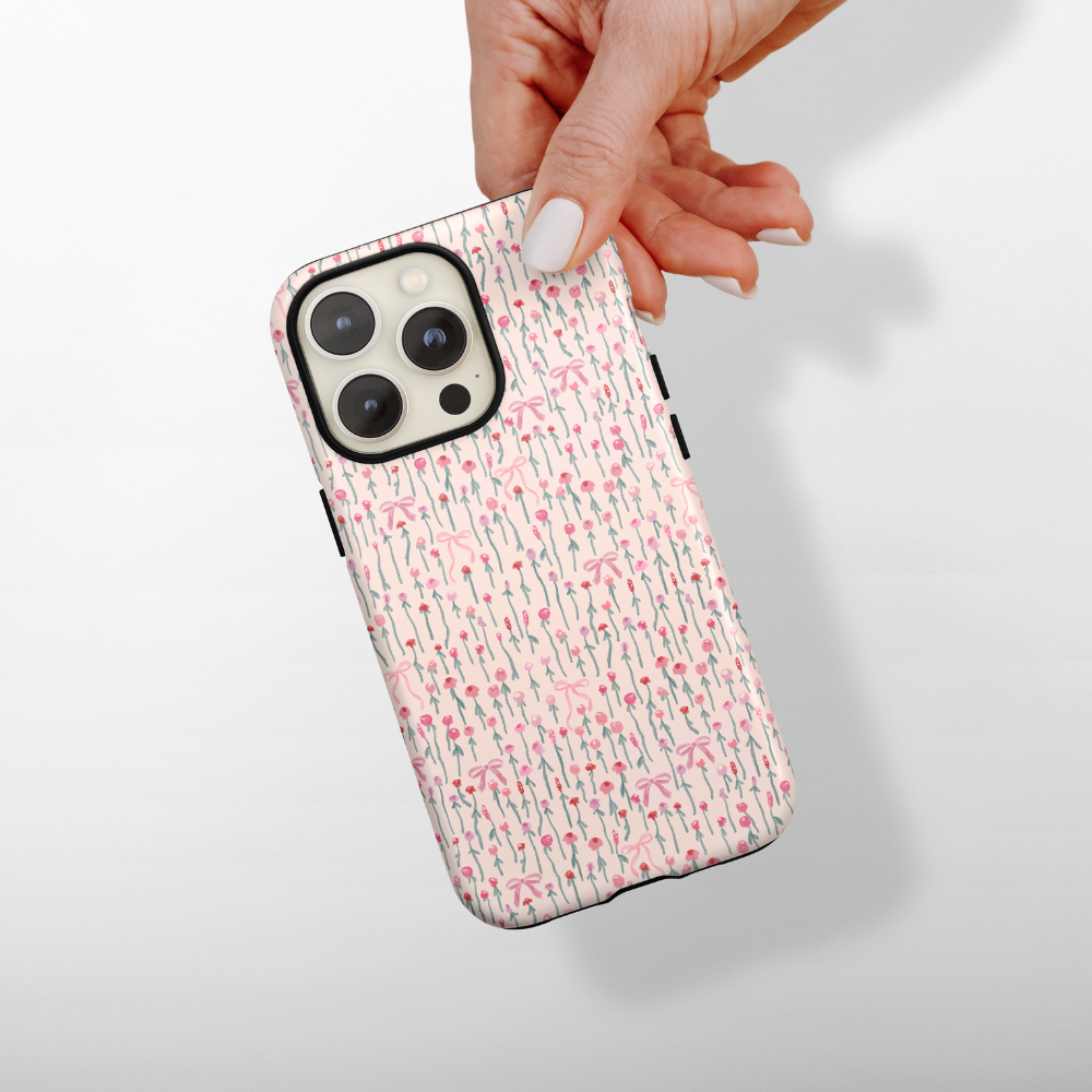 Hand holding a white Coconut Lane tough phone case with pink flower pattern.