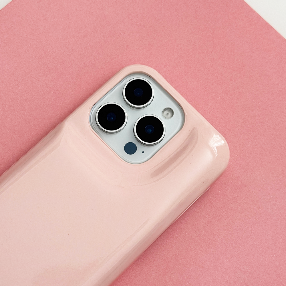 Close-up of glossy pastel pink Coconut Lane puffer phone case with embossed logo, displayed diagonally on a matching pink background.