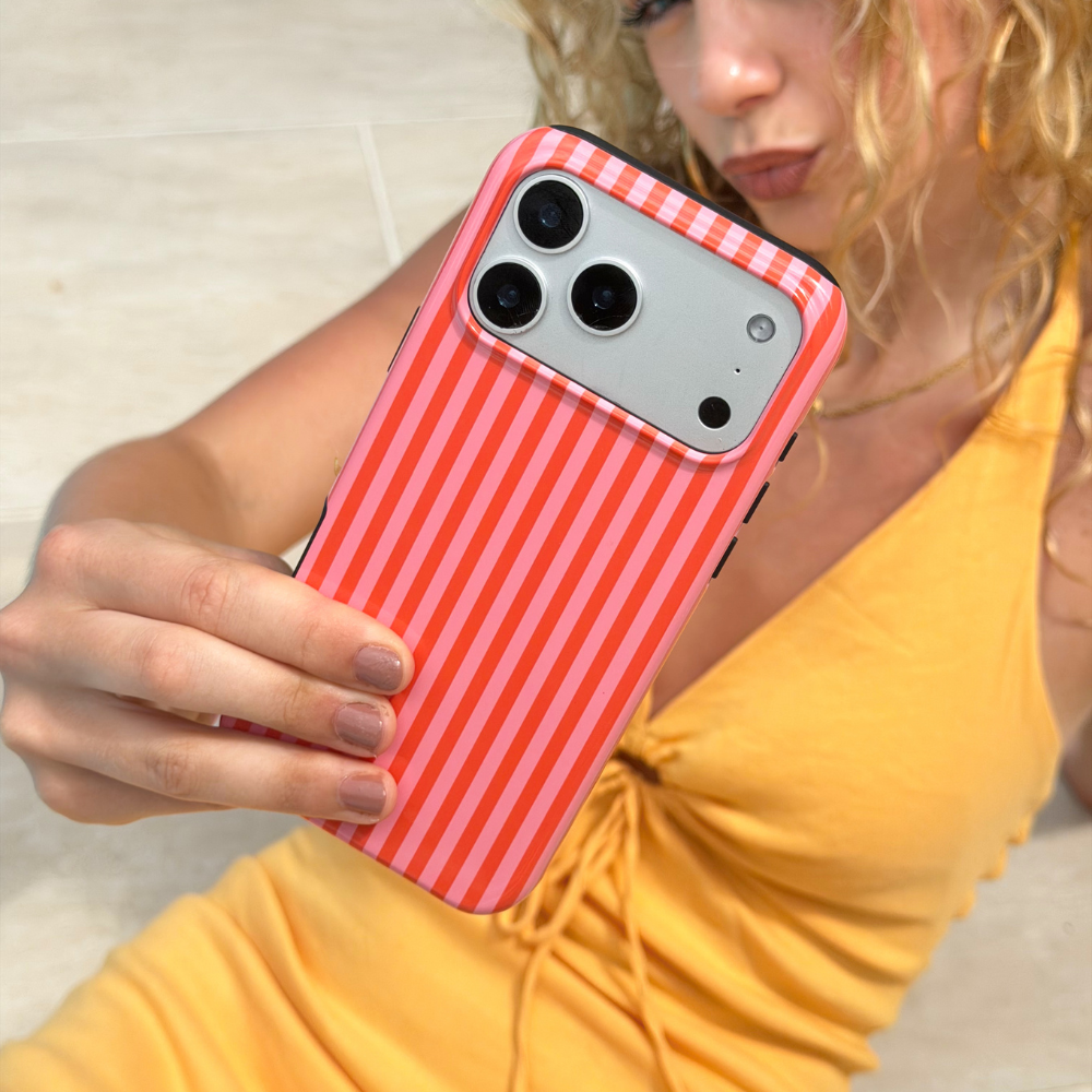 Person holding a phone with a orange and pink striped case