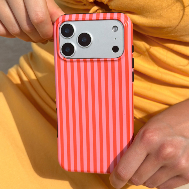 Person holding a phone with a orange and pink striped case against a yellow background