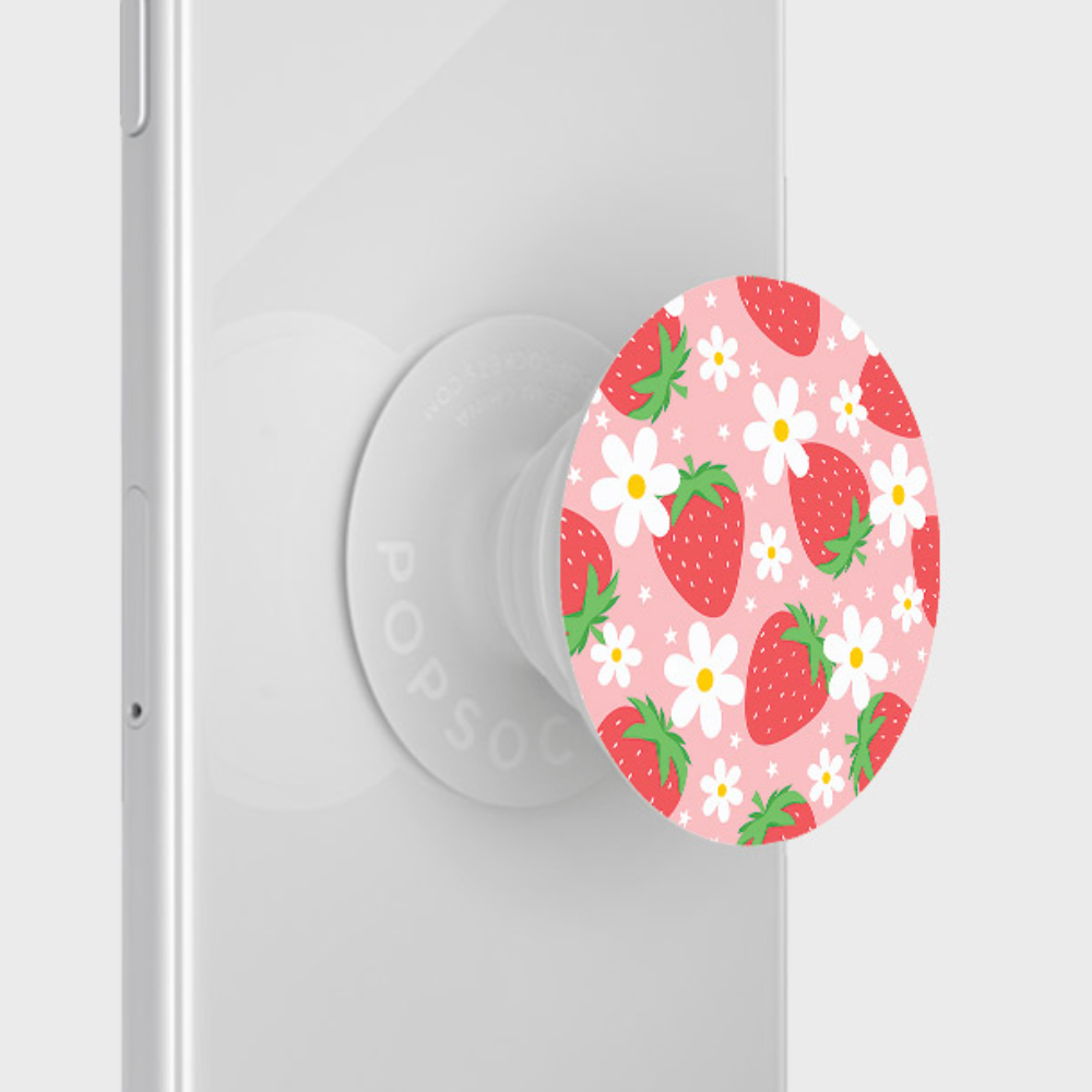 A white smartphone is equipped with the PopSocket Grip - Berry Cute Strawberry by Coconut Lane, which features a pink background adorned with strawberries and white flowers, making it the perfect phone accessory for a secure grip.