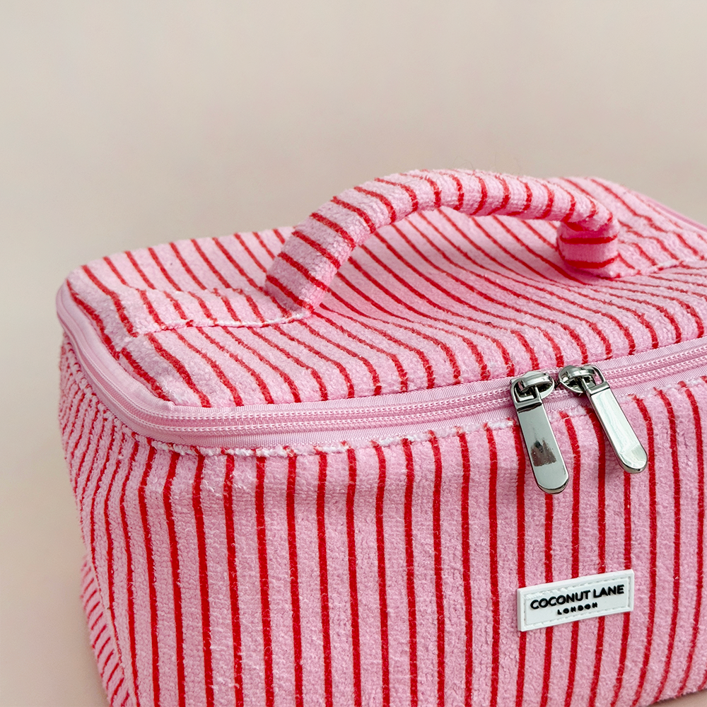 Pink and red striped makeup bag with Coconut Lane brand label on a beige background