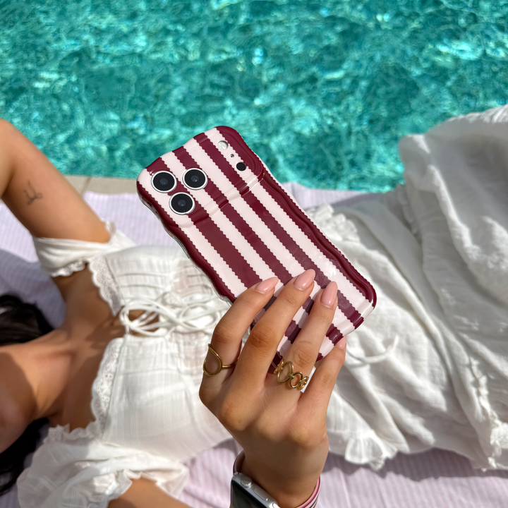 Girl taking a selfie by the pool holding wavy blushberry scallop stripes phone case
