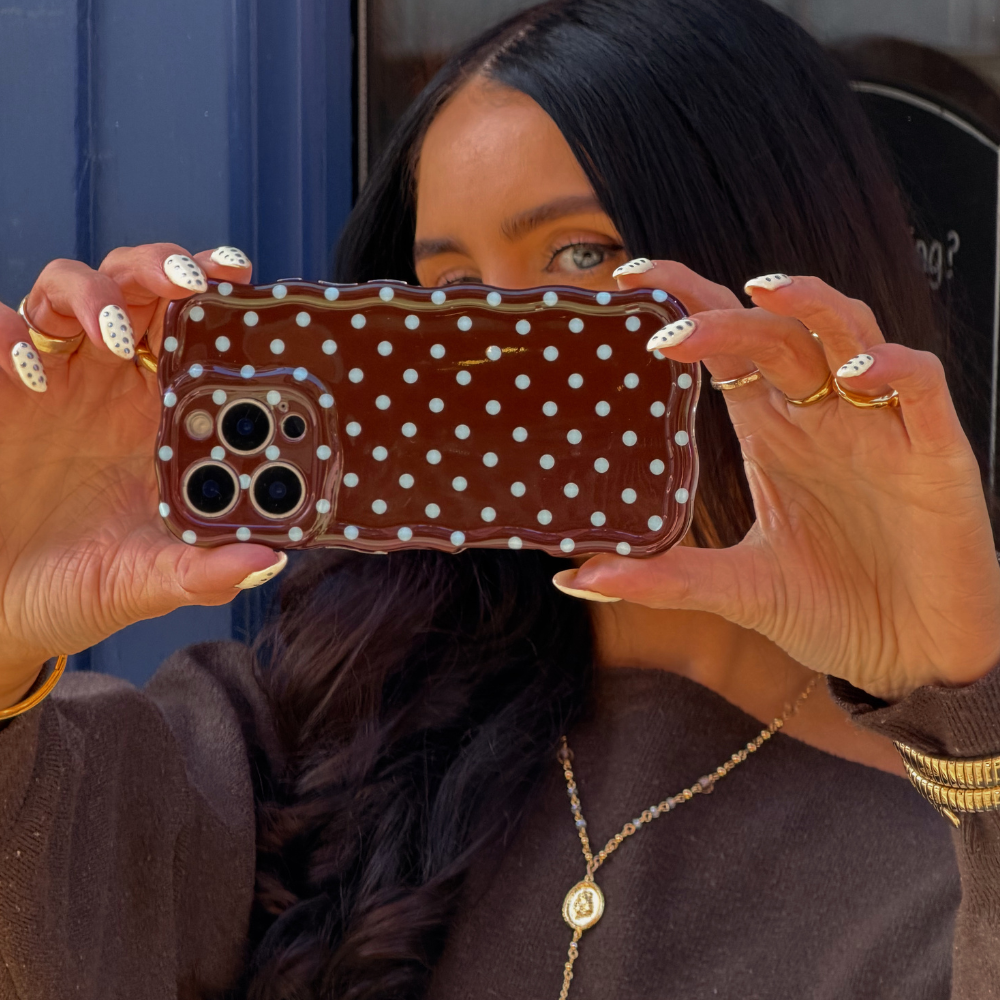 Girl taking selfie close up image of wavy brown and blue polka dot phone case