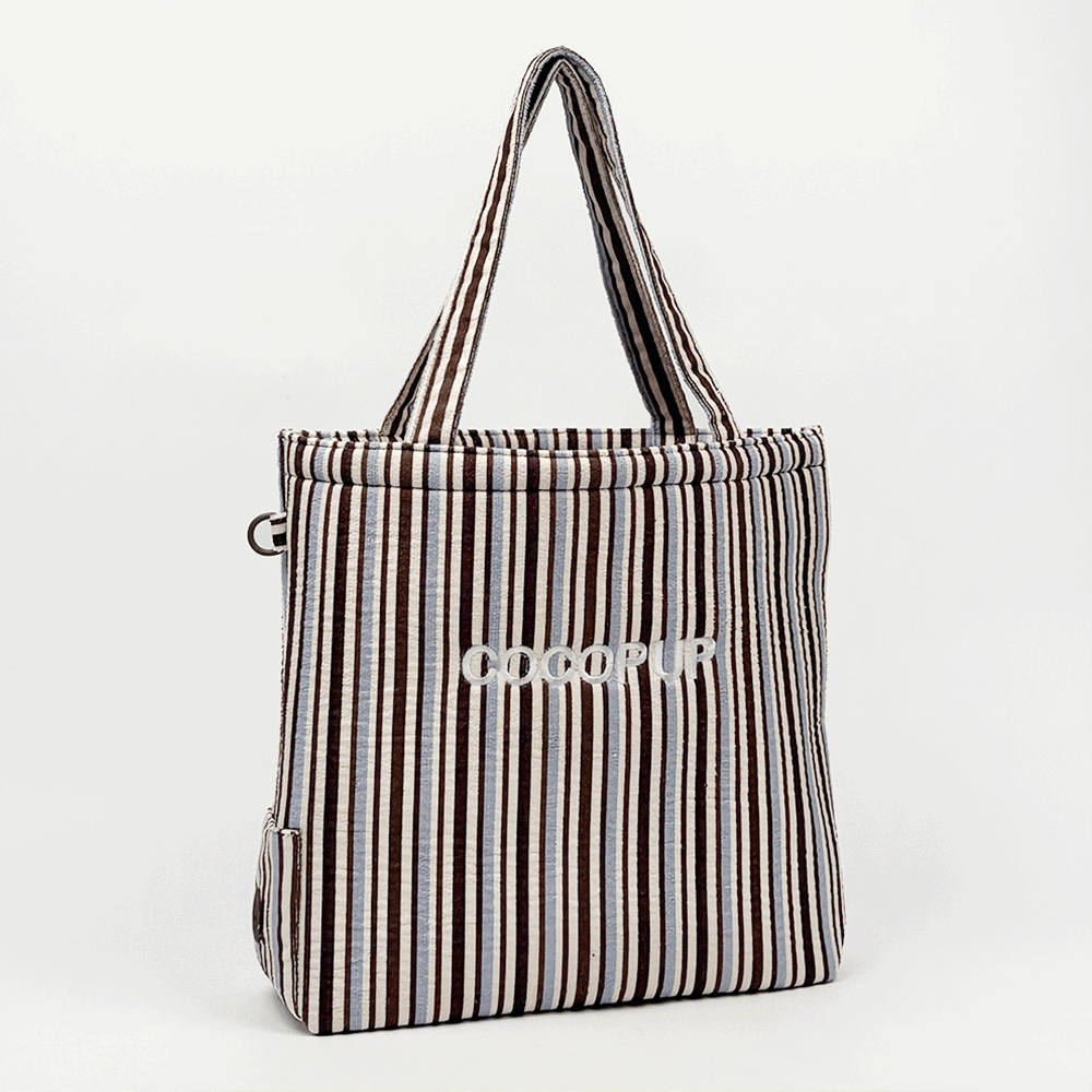Tote bag with brown and blue stripes, towel-inspired texture, and sturdy handles.