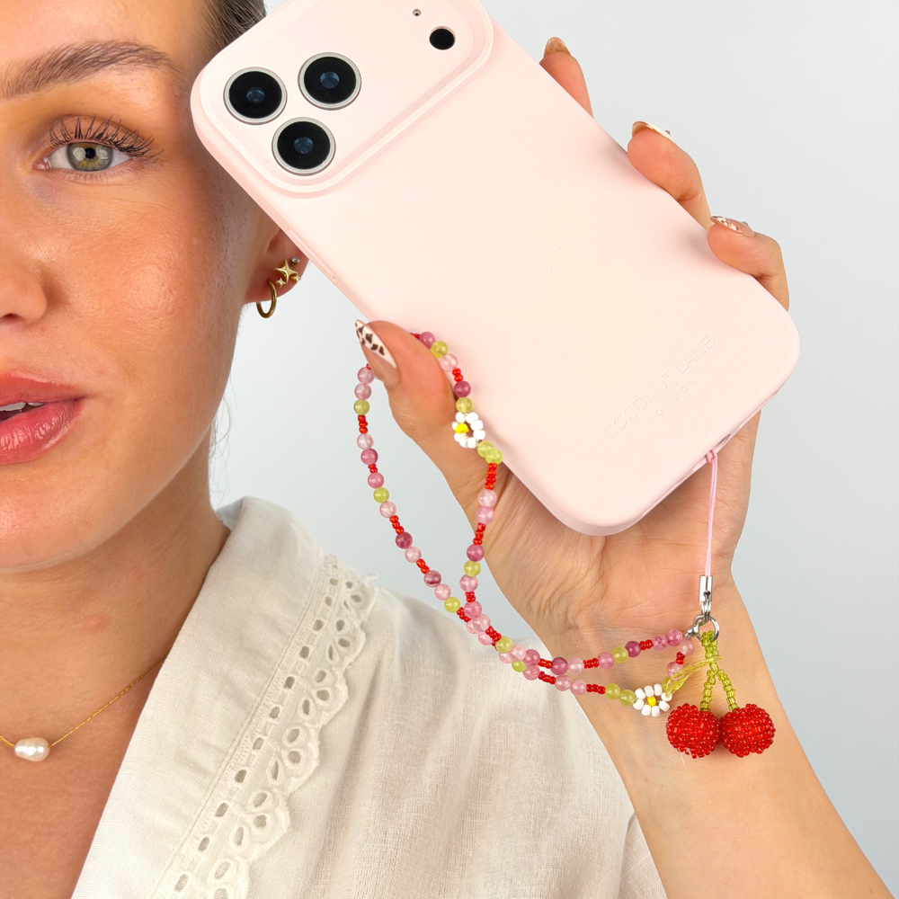 girl posing next to her butter soft phone case in pink with her cherry bomb phone strap attached