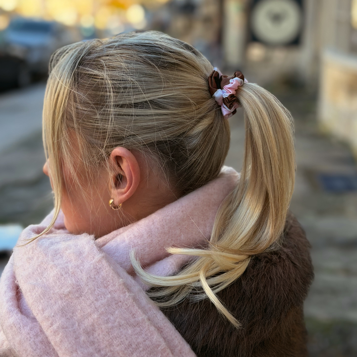 Woman with blonde hair wearing a Satin hair scrunchie in a brown, pink and white striped design.