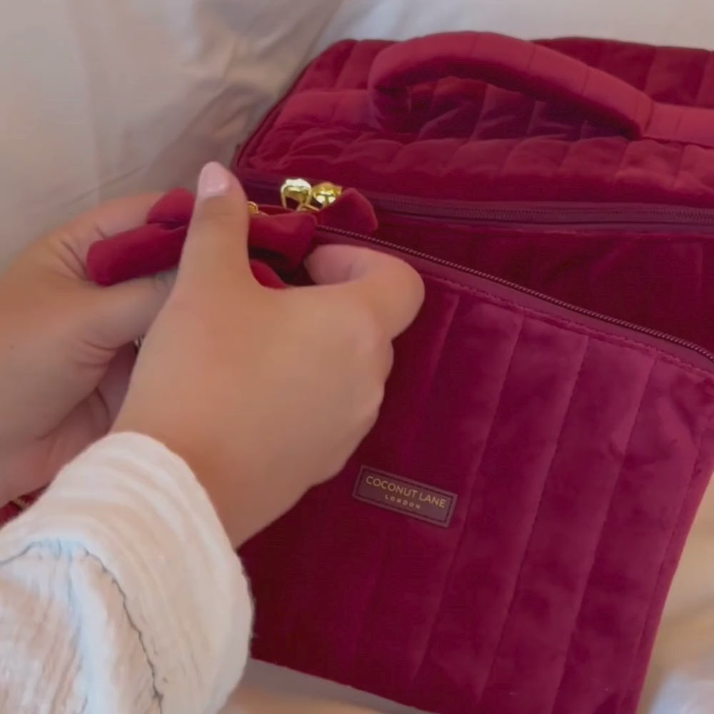 Burgundy velvet cosmetic bag with a quilted design, bow detail, and gold-tone hardware.
