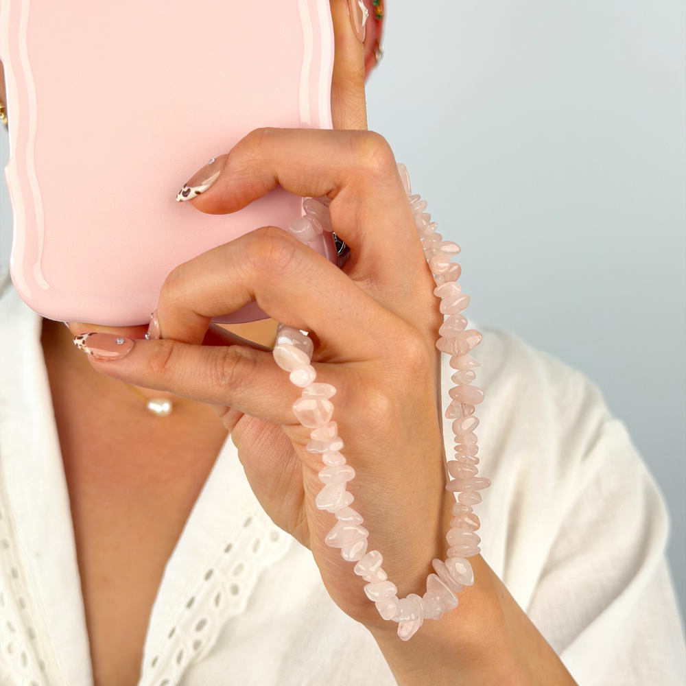 Girl with her rose quartz phone strap around her wrist attached to a pink phone case
