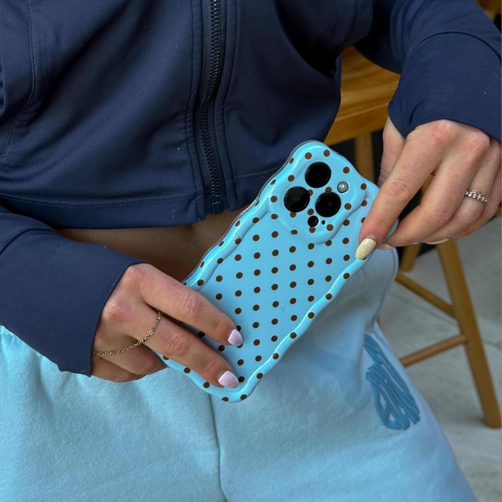 close up of girl holding wavy blue polka dot phone case
