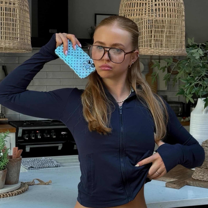 Girl in a kitchen holding a wavy blue polka phone case